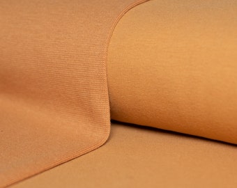 May include: Close-up of a soft, brown fabric with a textured surface. The fabric is folded in half, creating a smooth, even fold.