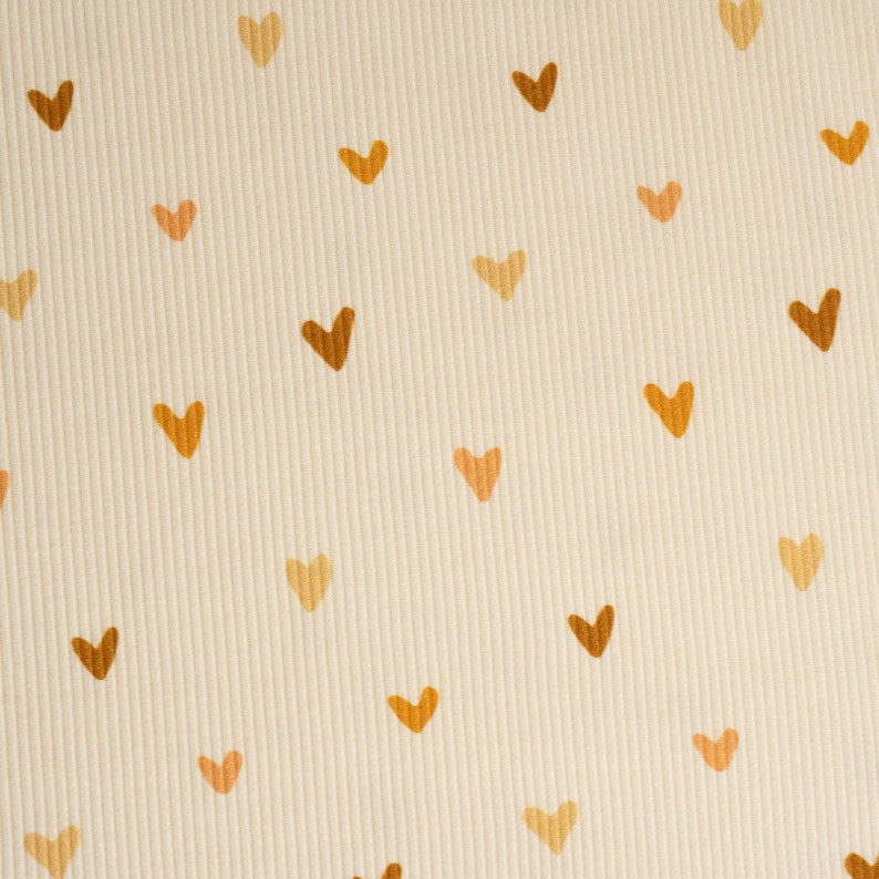 May include: A cream-colored fabric with a repeating pattern of brown and orange hearts.
