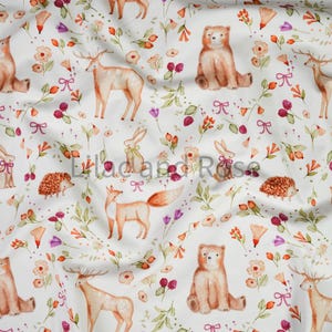 May include: White fabric featuring a repeating pattern of woodland creatures and floral designs. The pattern includes deer, bears, foxes, rabbits, and hedgehogs, with flowers and bows in orange, pink, and purple hues.