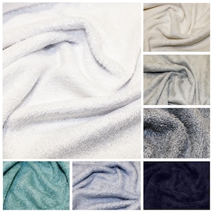 May include: A collage of close-up shots of soft, plush fabric in various colors. The colors include white, cream, gray, teal, light blue, and navy. The fabric has a textured, fuzzy appearance, suggesting a cozy material.