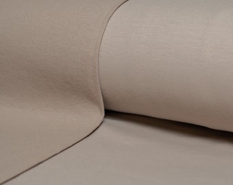 May include: Close-up of a beige fitted sheet with a smooth texture. The sheet is folded over itself, showing the underside of the fabric.