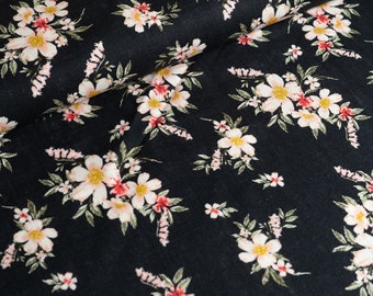 May include: Black fabric with a white and pink floral pattern. The fabric has a subtle texture and a repeating pattern of small flowers.