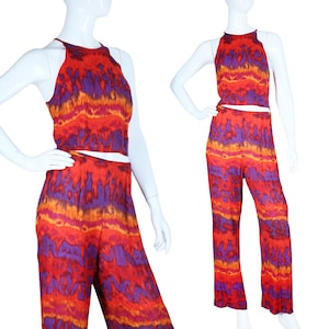 May include: A two-piece outfit with a halter top and wide-leg pants. The fabric is a red, orange, and purple tie-dye pattern.