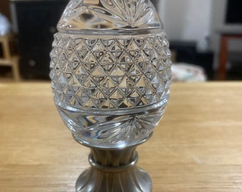 May include: A clear glass bottle stopper with a diamond pattern and a silver base.