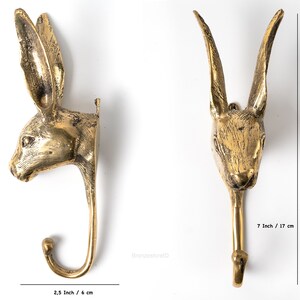 May include: A gold-toned metal rabbit head wall hook with a hook extending from the bottom. The hook is 7 inches tall and 2.5 inches wide.