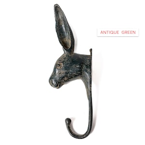 May include: Antique green rabbit head wall hook. The hook is shaped like a rabbit's head with long ears and a curved hook.