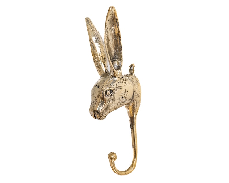 May include: A gold-colored metal rabbit head wall hook. The hook is shaped like a rabbit's head with long ears and a curved hook at the bottom.
