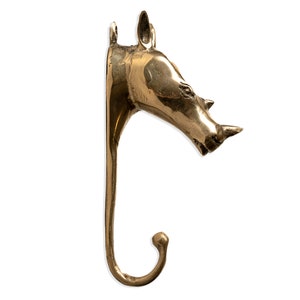 May include: A gold-toned metal rhino head wall hook. The hook is shaped like a rhino's head with a curved hook extending from the bottom.
