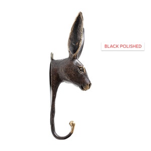 May include: Black polished bronze rabbit head wall hook. The hook is shaped like a rabbit's head with long ears and a curved hook for hanging items.