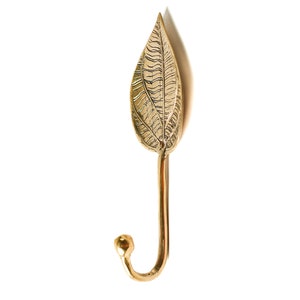 May include: A gold leaf-shaped hook with a detailed design. The hook is made of metal and has a simple, elegant design.