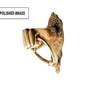 Puede incluir: Aldaba de puerta de lat&oacute;n pulido con forma de pu&ntilde;o, con una placa trasera ornamentada. El texto "POLISHED BRASS" est&aacute; en un recuadro blanco. La aldaba es de color oro c&aacute;lido.