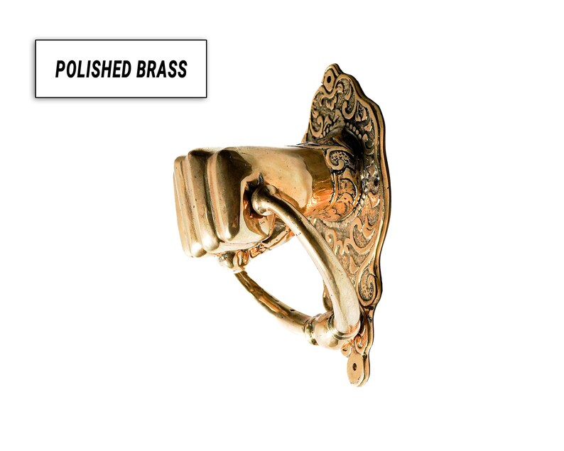 Puede incluir: Aldaba de puerta de lat&oacute;n pulido con forma de pu&ntilde;o, con una placa trasera ornamentada. El texto "POLISHED BRASS" est&aacute; en un recuadro blanco. La aldaba es de color oro c&aacute;lido.