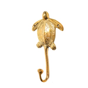 May include: A gold-toned metal turtle hook. The turtle is detailed with a shell pattern and has a hook extending from its tail.
