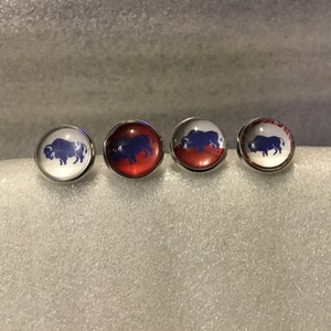 May include: Four silver-toned round buttons with a blue buffalo silhouette on a white background. The buttons have a red, white, and blue design.