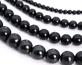 May include: A strand of black beads, with multiple strands of varying lengths, arranged in a circular pattern. The beads are smooth and glossy, with a slight sheen.