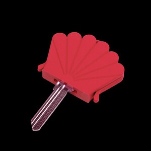 May include: A metal key with a bright red plastic cover shaped like a fan or a seashell. The key blade is silver-colored with a textured surface, while the head of the key is encased in a solid red, semi-circular housing with radiating lines.