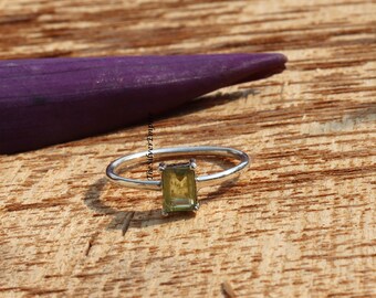 May include: A silver ring with a green gemstone set in a rectangular shape.