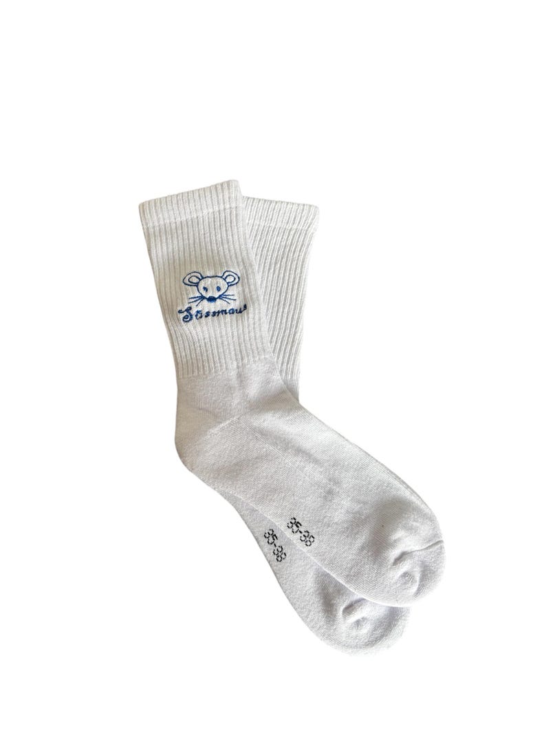May include: A pair of white socks with a blue embroidered mouse design and the word "Sossmou" above the mouse. The socks have a ribbed texture and the size "35-38" is printed on the foot.
