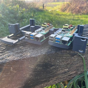 Könnte beinhalten: Zwei schwarze 3D-gedruckte Gehäuse mit Leiterplatten und USB-Anschlüssen im Inneren. Die Gehäuse befinden sich auf einer verwitterten Holzoberfläche.
