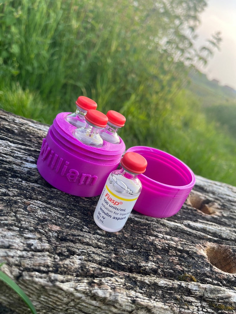 Peut inclure: Un r&eacute;cipient violet imprim&eacute; en 3D avec le mot "William" imprim&eacute; dessus. Le r&eacute;cipient contient quatre petits flacons en verre avec des bouchons rouges. Un seul flacon avec un bouchon rouge et une &eacute;tiquette qui indique "Fiasp&reg; 100 unit&eacute;s/mL solution injectable insuline aspart SC, IV 10 mL" est plac&eacute; &agrave; c&ocirc;t&eacute; du r&eacute;cipient.