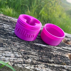 Peut inclure: Un r&eacute;cipient en plastique rose avec le mot "William" imprim&eacute; sur le c&ocirc;t&eacute;. Le r&eacute;cipient est ouvert et le couvercle est &agrave; c&ocirc;t&eacute;.