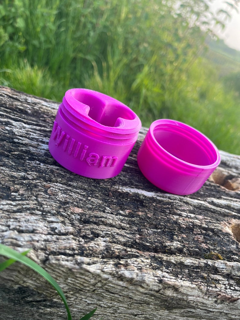 Peut inclure: Un r&eacute;cipient en plastique rose avec le mot "William" imprim&eacute; sur le c&ocirc;t&eacute;. Le r&eacute;cipient est ouvert et le couvercle est &agrave; c&ocirc;t&eacute;.