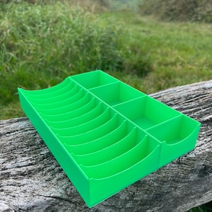 May include: A bright green plastic organizer with multiple compartments. The organizer has a curved design and is ideal for storing small items.