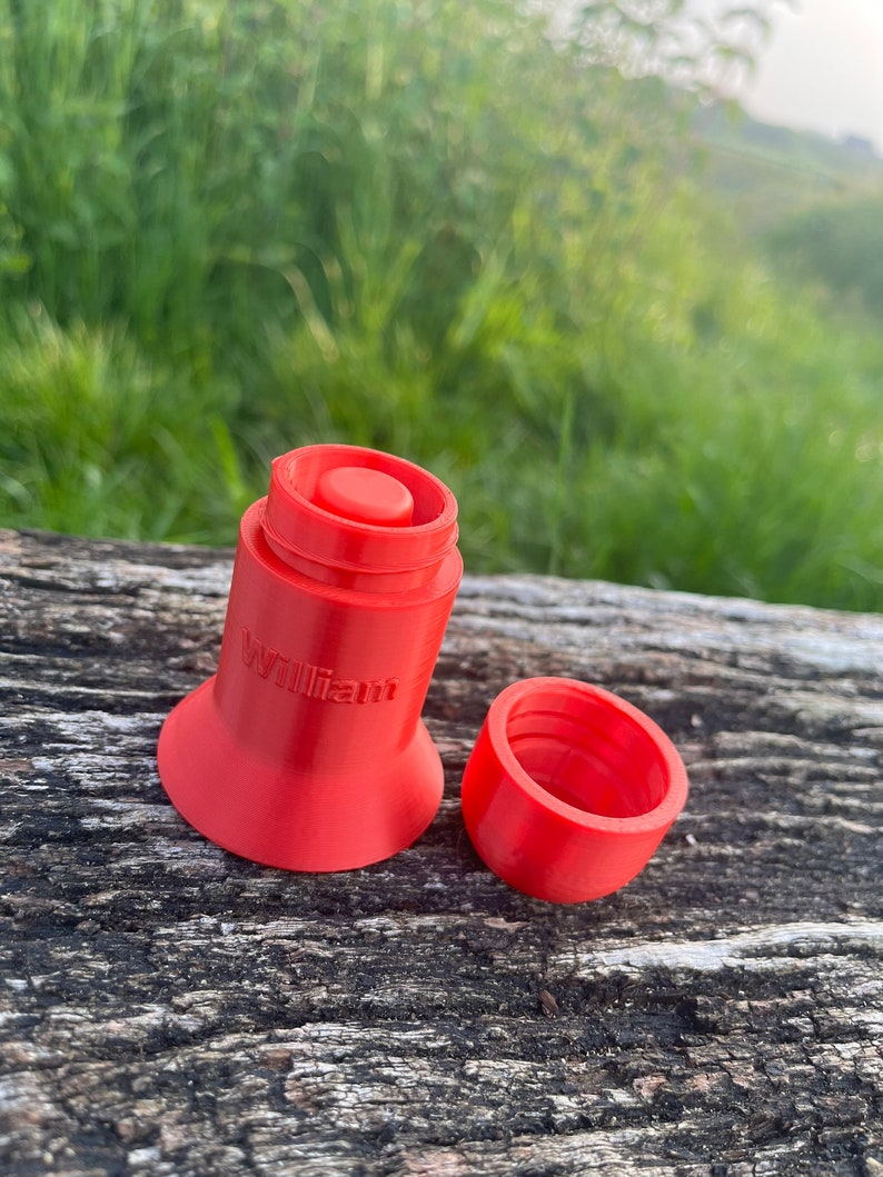 Peut inclure: Un r&eacute;cipient rouge vif imprim&eacute; en 3D avec le mot "william" imprim&eacute; sur le c&ocirc;t&eacute;. Le r&eacute;cipient est ouvert et le couvercle est pos&eacute; &agrave; c&ocirc;t&eacute;.