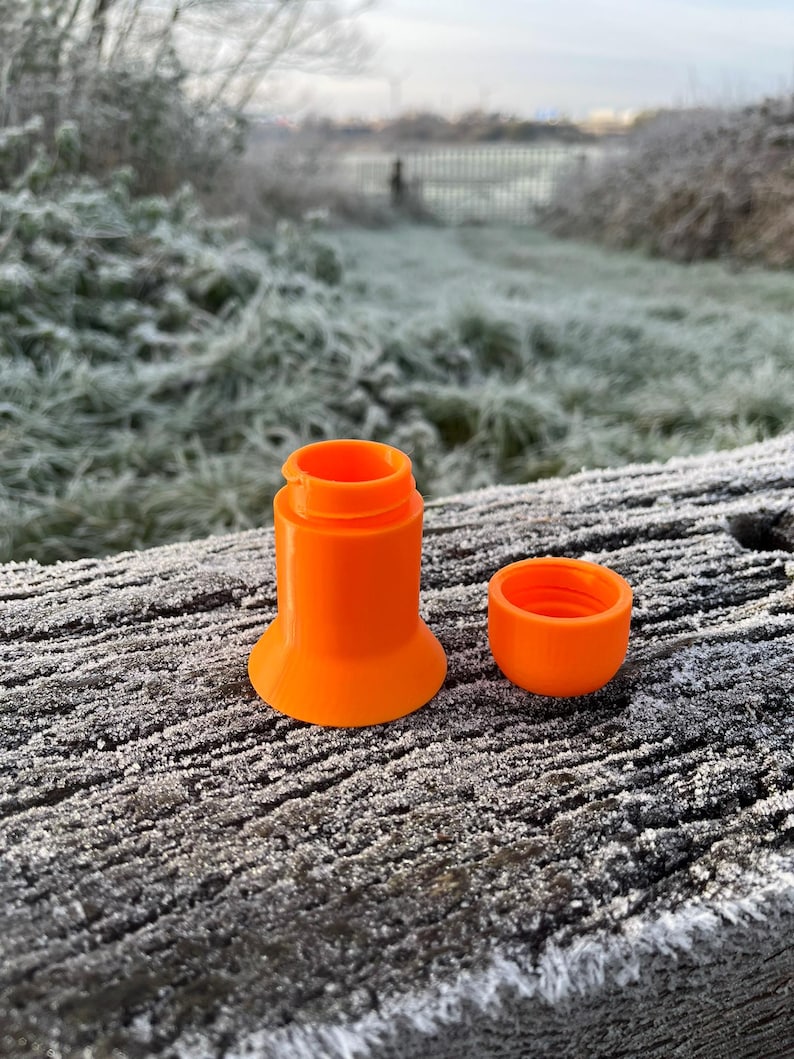 Peut inclure: Un r&eacute;cipient en plastique orange vif avec un couvercle. Le r&eacute;cipient est compos&eacute; de plusieurs pi&egrave;ces qui s'embo&icirc;tent. Le r&eacute;cipient est pos&eacute; sur une surface en bois recouverte de givre.
