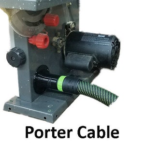 May include: A close-up of a black and green dust collection hose attached to a gray table saw. The saw has a black motor and red knobs. The text "Porter Cable" is visible below the saw.