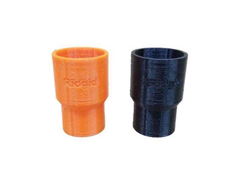 K&ouml;nnte beinhalten: Zwei 3D-gedruckte Kunststoffverbinder, einer orange und einer schwarz. Der orangefarbene Verbinder hat die Aufschrift "Ridgrid" auf der Seite.