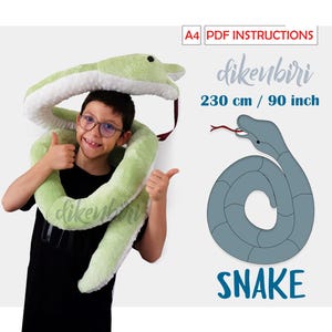 May include: A green plush snake toy, 90 inches long, is being worn as a necklace by a child. The snake is curled around the child's neck and shoulders. The child is smiling and giving a thumbs up. The image also includes a line drawing of a snake with the text "SNAKE" underneath.