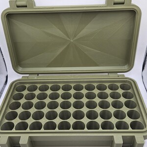 May include: An olive green rectangular storage case with a hinged lid and two front latches. The interior features a grid of forty-eight circular compartments for organizing small items. The lid interior has a geometric starburst pattern.