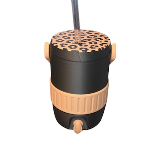 May include: Black and tan insulated tumbler with a leopard print lid and a clear straw. The tumbler has a tan band around the middle and a spigot at the bottom. The tumbler has two tan handles.