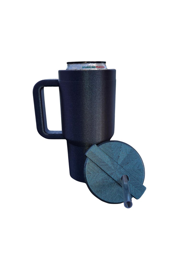 May include: A dark navy blue textured can cooler with a handle, holding a Sparkling Peach beverage can. A matching circular lid with a geometric pattern and a clear plastic straw is positioned in front of the cooler on a white background.