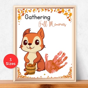 May include: A framed print with a cartoon squirrel holding a basket of acorns. The print features the text "Gathering Fall Memories" and a handprint. A red circle indicates "3 Sizes". The frame is light brown.