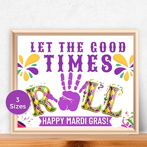 May include: A framed print with the text "LET THE GOOD TIMES ROLL" in purple. The word "ROLL" is in a festive font with Mardi Gras colors. The phrase "HAPPY MARDI GRAS!" is at the bottom.