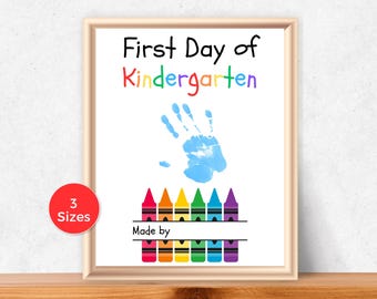 May include: A framed print with the text "First Day of Kindergarten" in colorful letters. A blue handprint is above a row of colorful crayons. The print includes a space to write "Made by". A red circle indicates "3 Sizes".