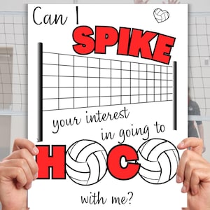 Pode incluir: Um cartaz branco com um gráfico de rede de voleibol e as palavras "Can I SPIKE your interest in going to HOCO with me?" em preto e vermelho. Duas mãos seguram o cartaz.