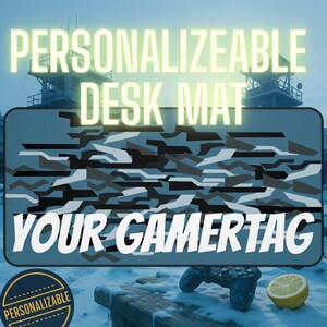May include: A rectangular desk mat with a camouflage pattern in shades of gray and blue. The text "PERSONALIZABLE DESK MAT" is at the top, and "YOUR GAMERTAG" is at the bottom. A circular "PERSONALIZABLE" badge is in the lower left corner.
