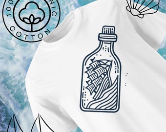 Puede incluir: Camiseta blanca con un contorno azul de una botella con un barco dentro. El texto "100% Algodón Orgánico" está en un círculo en el lado izquierdo de la camiseta.