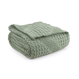 May include: A sage green blanket featuring a distinct waffle weave texture. The fabric is folded into a neat, rectangular stack, showcasing the uniform grid pattern across the entire surface of the textile. The material has a soft, matte appearance.