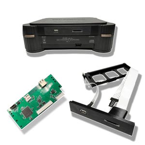 May include: A black gaming console with a green circuit board, a black and white cable, and a black accessory with a USB port and a memory card slot. The console has the text "RE-VAL 3DD INTERACTIVE MULTIPLAYER FZ-1" on the front.