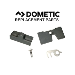 Op de afbeelding: Een set van vier vervangende onderdelen voor een Dometic koelkast. De onderdelen omvatten twee grijze kunststof onderdelen, een kleine zilveren schroef en een zilveren metalen haak.