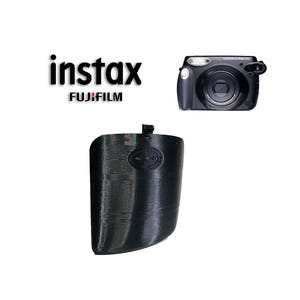 Puede incluir: Funda de cámara negra con una superficie texturizada y la palabra "instax" impresa en ella. La funda está diseñada para adaptarse a una cámara Fujifilm Instax.