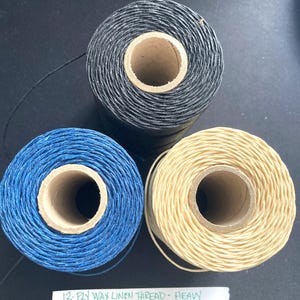 May include: Three spools of 12-ply waxed linen thread. The spools are black, blue, and beige. The text on the label reads "12-PLY WAX LINEN THREAD - HEAVY".