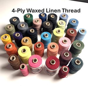 May include: A collection of 4-Ply Waxed Linen Thread spools in a wide variety of colors including red, yellow, blue, green, pink, brown, and black. The spools are arranged in a cluster, and the text 4-Ply Waxed Linen Thread is visible at the top.