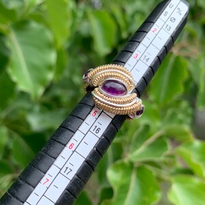 Peut inclure: Une bague en or et argent avec des pierres précieuses violettes. La bague est mesurée sur un calibre à anneaux qui indique une taille 6, ce qui équivaut à 17 mm.