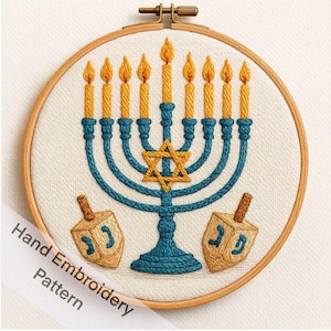 May include: Hand-embroidered menorah and dreidels on cream fabric, in a wooden hoop. The blue menorah has yellow candles, and the tan dreidels have blue Hebrew letters. The text "Hand Embroidery Pattern" is on a diagonal across the image.