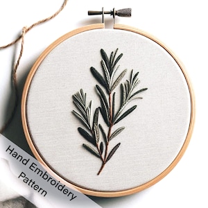 May include: A hand-embroidered pattern of a green leafy branch in a wooden embroidery hoop. The text "Hand Embroidery Pattern" is visible in the lower left corner of the image.